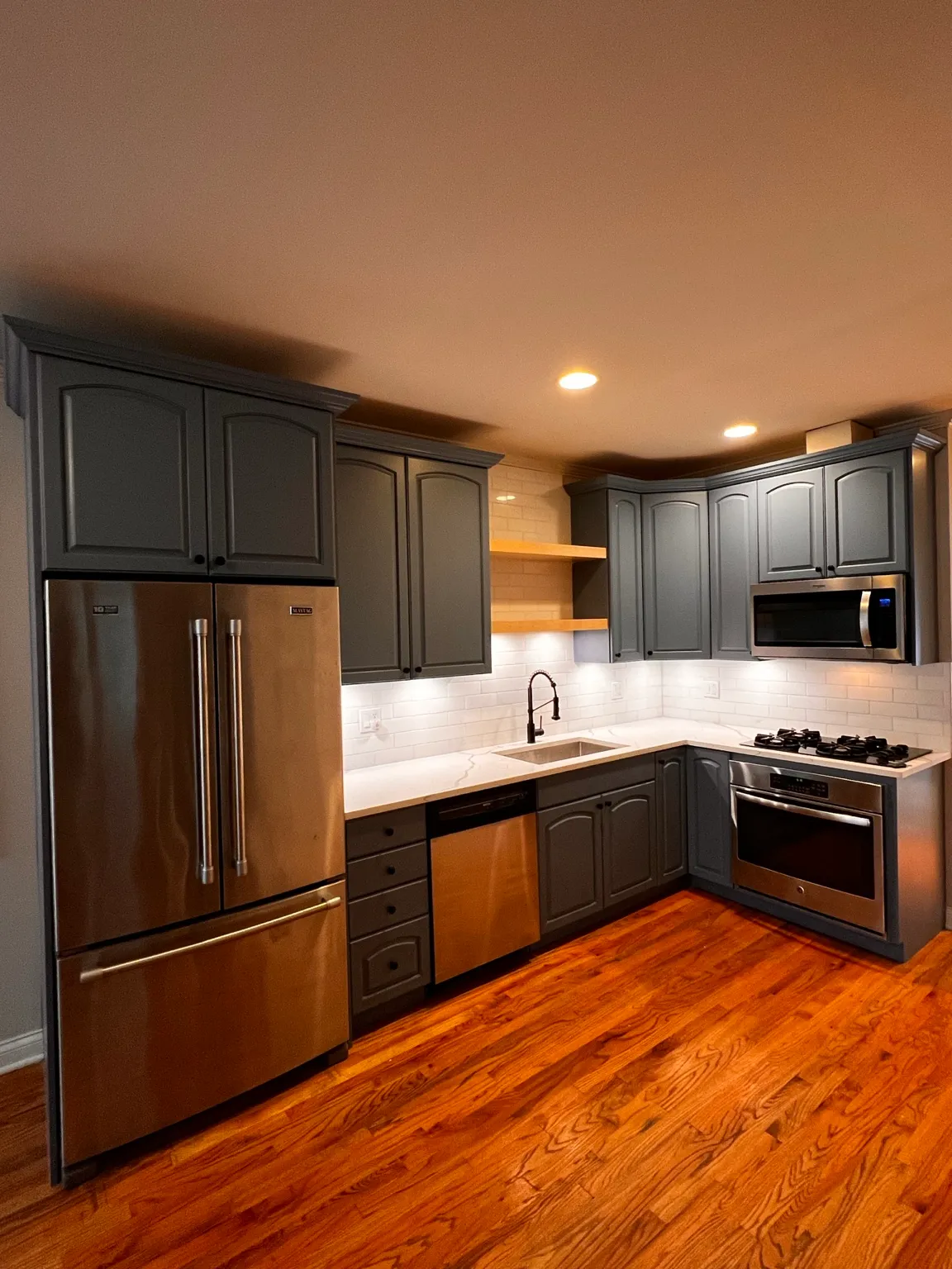 Finished kitchen with charcoal cabinetry, white counters and stainless appliances