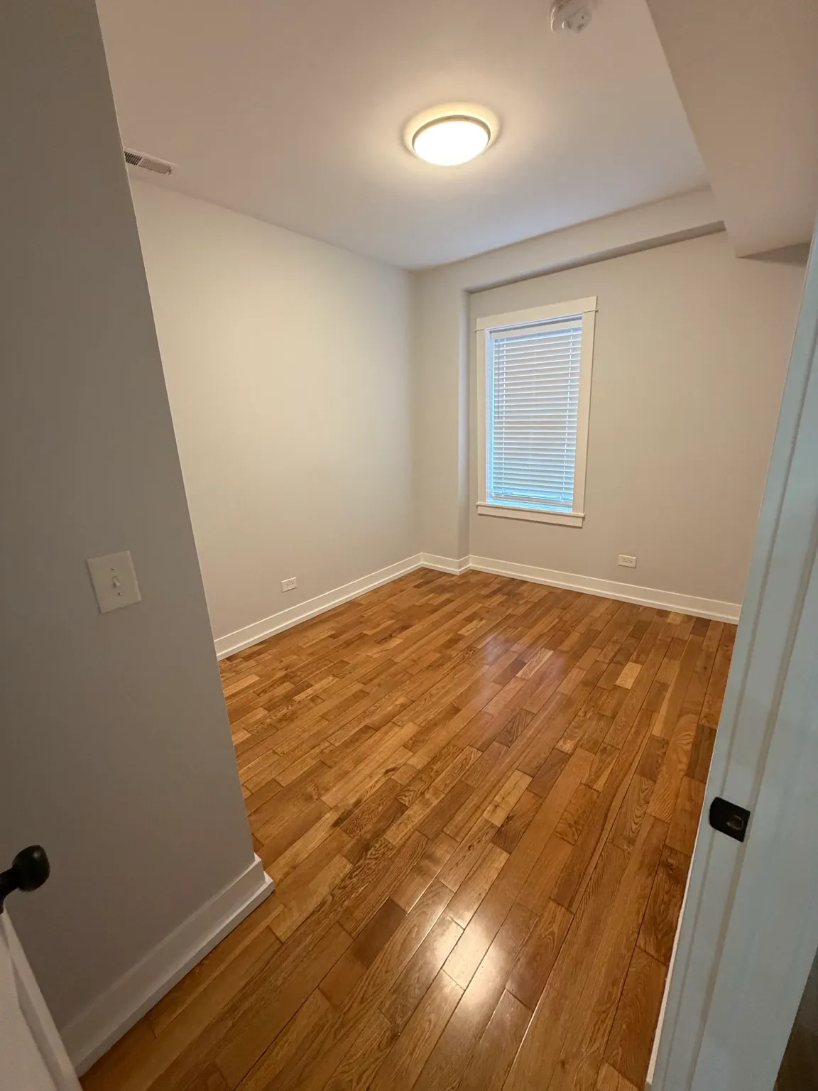 Finished small room with light walls, white trim and hardwood floor