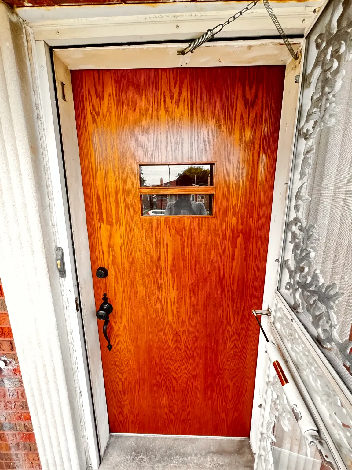 Refinished oak entry door with warm amber wood tone and dark hardware